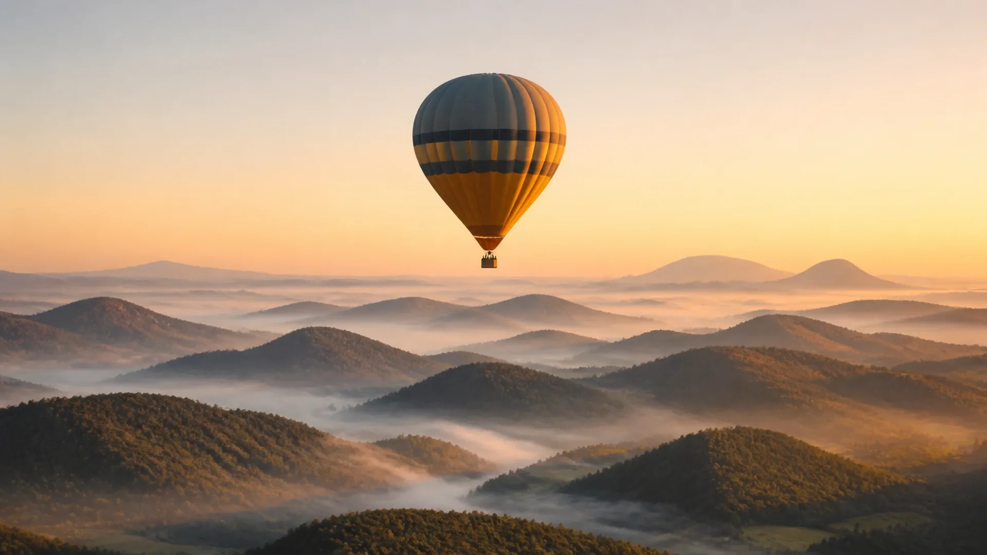 Hot air balloon aloft at sunrise over the volcanoes with mist in the valleys