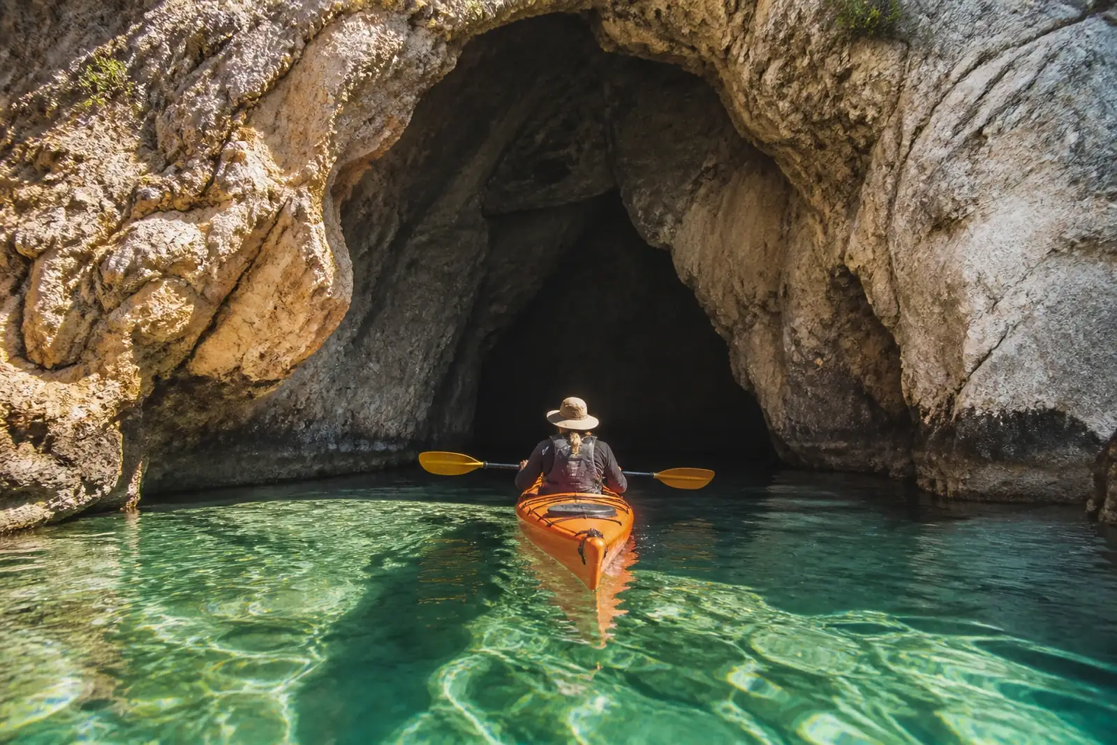 Sea kayak passing through a natural rock arch at the Montgrí caves